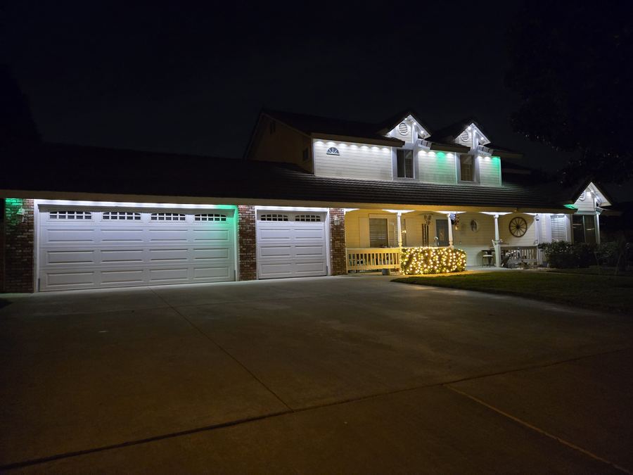 Home with warm white and green permanent lighting on the dormers and porch