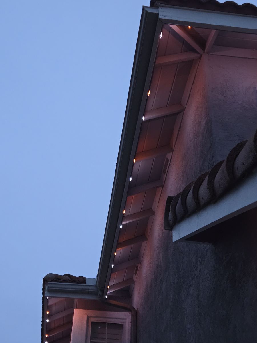 Close-up of amber lighting installed under the eaves at dusk